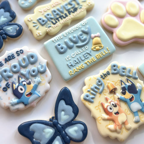 Bluey cookie set: hand-decorated character cookies with paw prints, butterflies, and a personalised name plaque in blue and cream