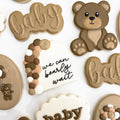 Baby shower cookies: a teddy bear, a we can bearly wait arch and baby script cookies in soft browns and cream
